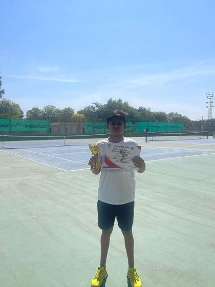 A solo shot of our U-14 Talent Series champion on an outdoor court, trophy in hand. We train our players to compete effectively in all types of environments.