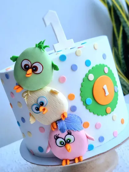 A cute Angry Birds-themed cake for a first birthday. The birds are sculpted from fondant and placed on a simple polka-dot cake.