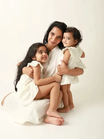 A hug full of happiness. This mother and her two daughters share a beautiful, smiling moment in their matching white dresses.