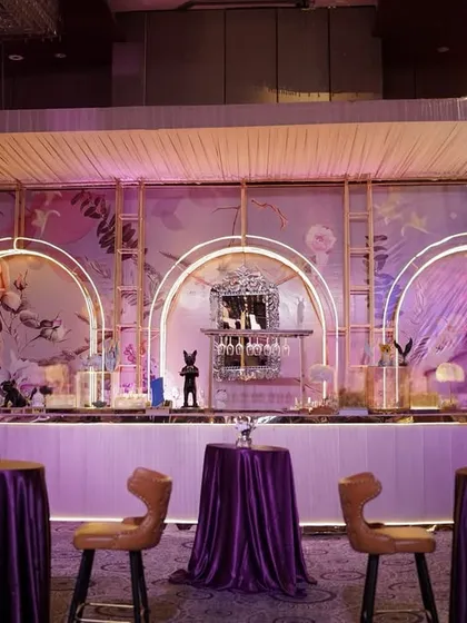 The grand bar setup, with its three illuminated arches, floral-painted backdrop, and elegant bar stools, created a stunning focal point for the celebration.