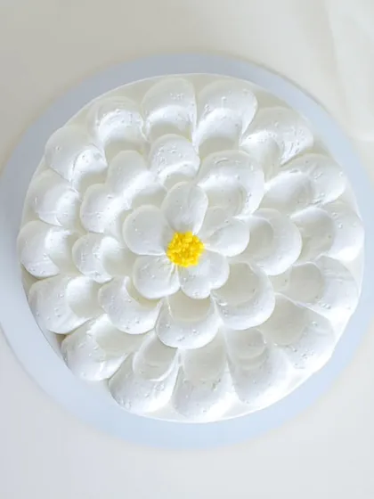 A simple and cheerful daisy cake. The petals are created with piped white chocolate ganache, making the entire cake a beautiful, edible flower.