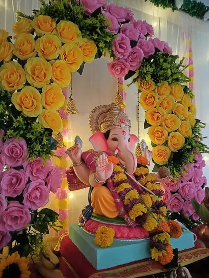 A close-up view of a vibrant floral arch using bright yellow and pink roses. This design brings a lot of color and joy to the Ganpati celebration, perfect for creating a festive atmosphere.