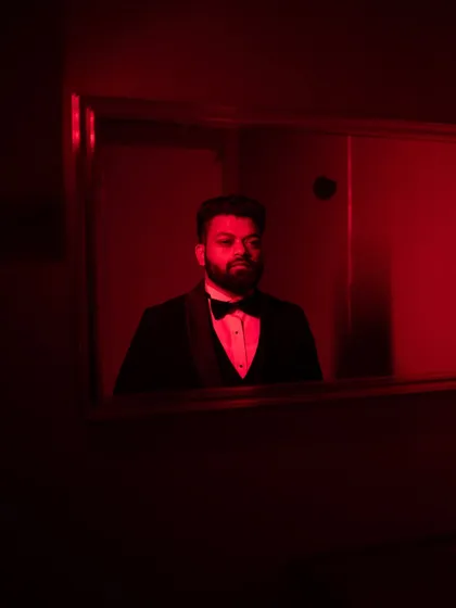 A moody and artistic groom portrait, using reflections and dramatic red light.