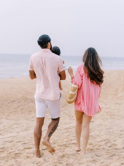 A family walking on the beach at sunset. The soft light and serene setting create a truly magical and romantic feel.