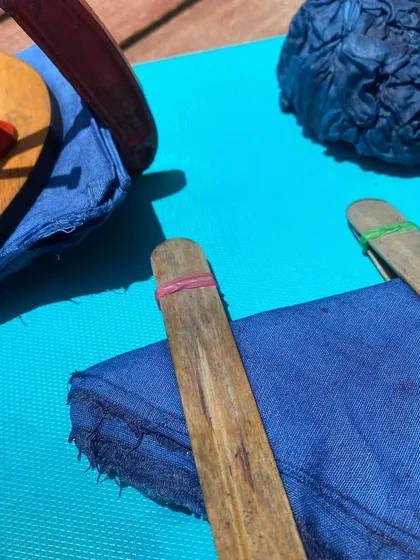 The tools of the trade for a Shibori tie-dye session. Wooden blocks, clamps, and rubber bands are used to create intricate and geometric resist patterns on the fabric.