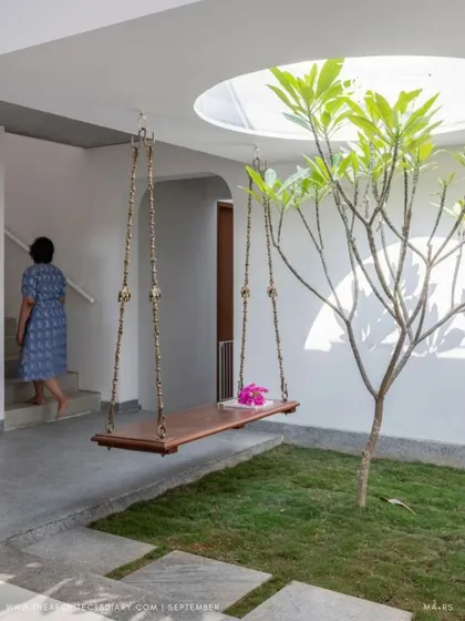 A resident ascends the stairs next to the central courtyard, showcasing how daily life circulates around this natural feature. The design ensures that movement through the house is always connected to light and greenery.