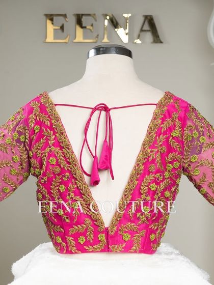 Grace in every detail. This pink net blouse features delicate leafy vines embroidered in gold and light green thread. The deep V-back and sheer sleeves add a touch of modern femininity.