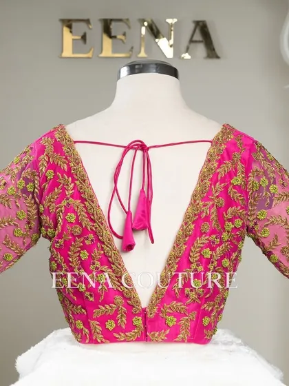 Grace in every detail. This pink net blouse features delicate leafy vines embroidered in gold and light green thread. The deep V-back and sheer sleeves add a touch of modern femininity.