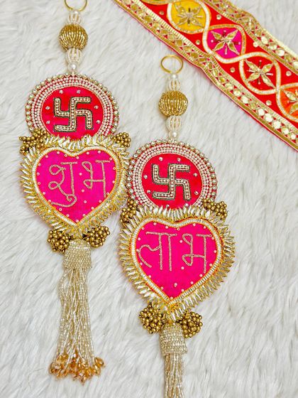 This heart-shaped Shubh Labh hanging in bright pink and gold is a lovely way to welcome guests. The design includes a swastika for extra blessings.