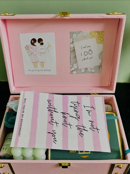 The moment of reveal for a bridesmaid proposal. The card inside the trunk reads, "I'm not tying the knot without you," a heartfelt message for a dear friend.
