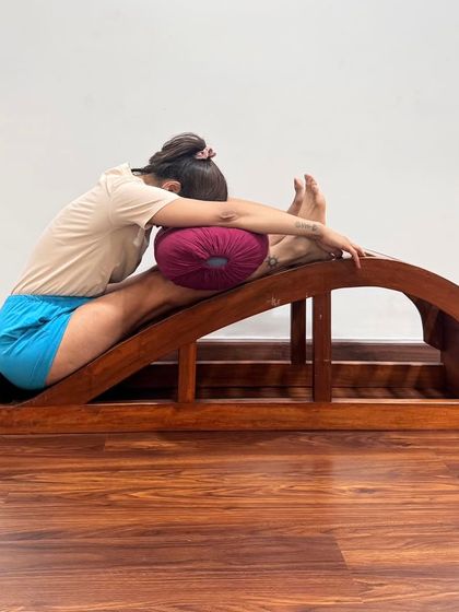 A supported forward bend using a backbend bench and bolster. This variation makes the pose accessible for those with stiff backs, providing a progressive stretch to make the spine supple.