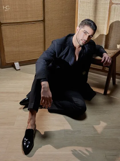 A more relaxed pose in the longline black achkan, showing its versatility and the commanding presence it holds even in a casual moment.