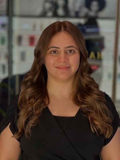 The lighting in the salon highlights the warm undertones of her new hair colour, showing its richness and depth.