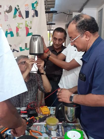 Teamwork makes the dream work. Multiple mentors and participants collaborate to fix an electric kettle, sharing knowledge and figuring out the solution together.