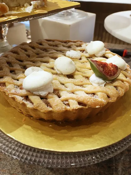 A beautiful lattice-topped fig pie, decorated with fresh figs and dollops of cream. A rustic yet elegant dessert.