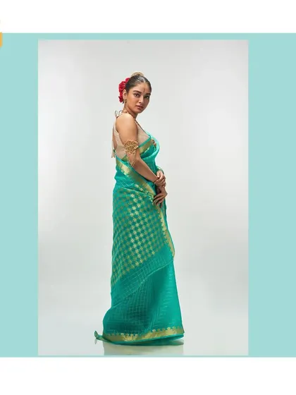 A side view of the light sea green saree, highlighting its serene color and the graceful way it drapes.