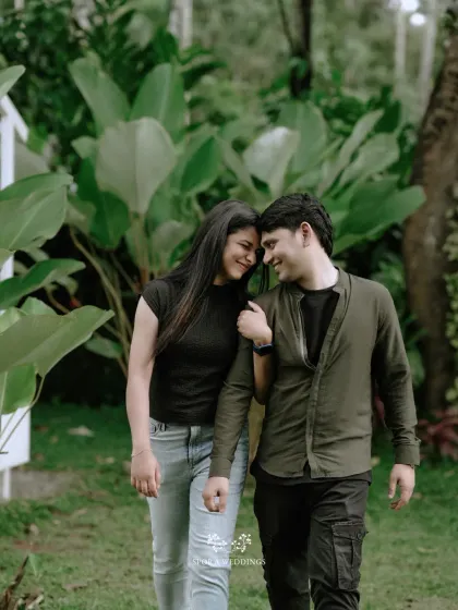 A happy, candid shot of the couple walking and laughing together in a beautiful garden.