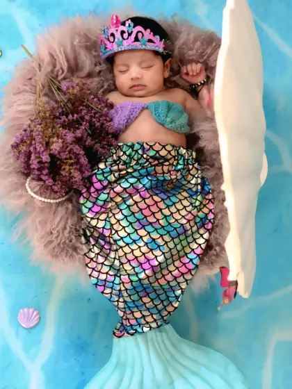 This newborn mermaid is ready for her close-up, dressed in a sparkling tail and crown while resting on a soft fur blanket.