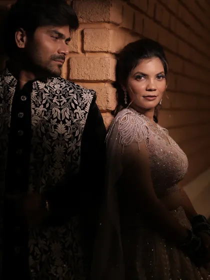 An artistic, moody portrait of the couple against a brick wall.
