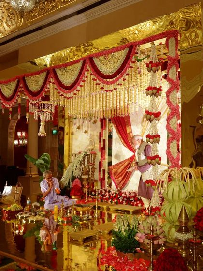 A closer look at the stunning South Indian mandap. The golden mirror structure is adorned with intricate floral garlands, creating a beautiful interplay of reflection, color, and tradition.