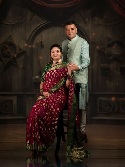 A formal and regal portrait of a couple in traditional Indian attire. The dark, ornate backdrop and classic posing give this maternity photo a timeless, almost royal quality.
