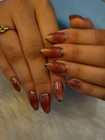 Let your nails do the talking with this sophisticated design. We created a beautiful reddish-brown ombré effect and added a delicate gold chrome line along the cuticle for a subtle touch of luxury.