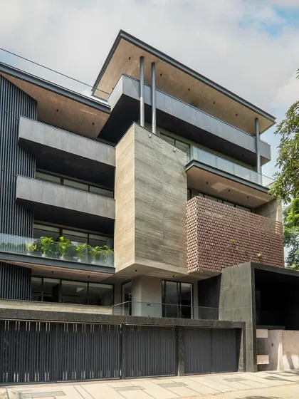 This modern facade in Gurugram is crafted with concrete, glass, and aluminum in an earthy-toned palette. The design concept of massing and volumes creates an expansive, airy feel.