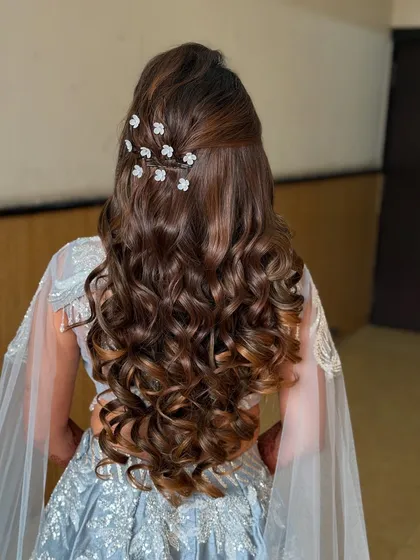 A view of the back, showcasing the voluminous soft curls and delicate hair accessories. This hairstyle is perfect for a sangeet or reception.