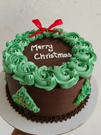 For a more elegant Christmas theme, I create these beautiful wreath cakes. This chocolate cake is decorated with green buttercream rosettes, silver dragées, and a festive red bow, perfect for a sophisticated holiday gathering.