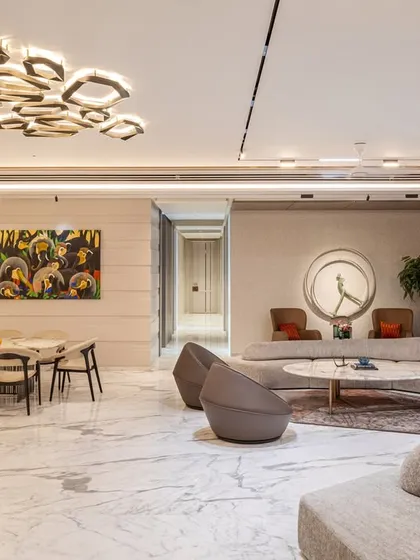 This bright and airy living room uses large marble floor tiles and expansive windows to create a sense of openness. We arranged the modular sofa and accent chairs to facilitate both large gatherings and quiet moments.