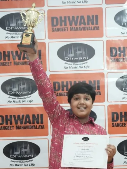 A student raises his trophy in victory, celebrating his win at the Mahotsav.