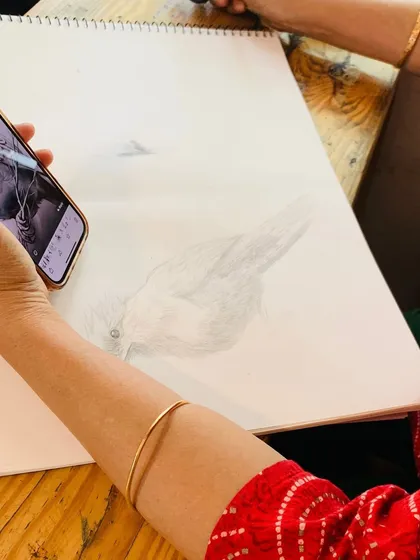 A student carefully shades a bird sketch, learning to build up layers of graphite to create a sense of volume.