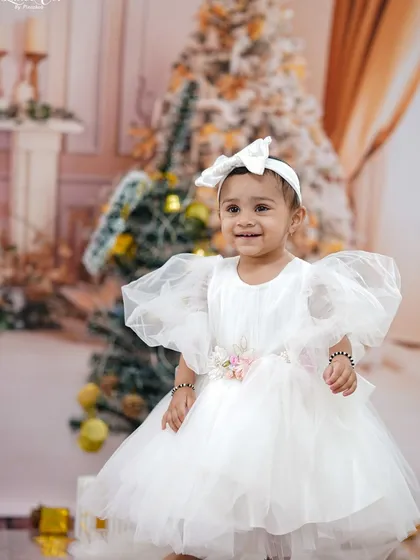 A close-up portrait of the birthday girl, her happy smile lighting up the Christmas-themed set.