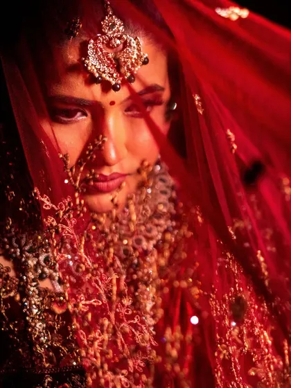 A mysterious and beautiful shot of the bride through her red veil. This artistic photo captures the essence of bridal beauty.
