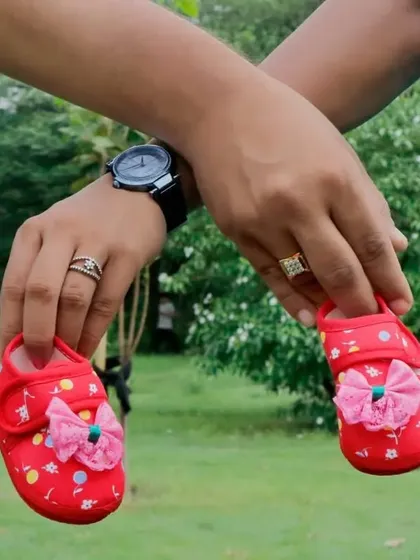 A close-up of the expecting parents holding a pair of tiny red baby shoes. This type of detail shot is perfect for pregnancy announcements.
