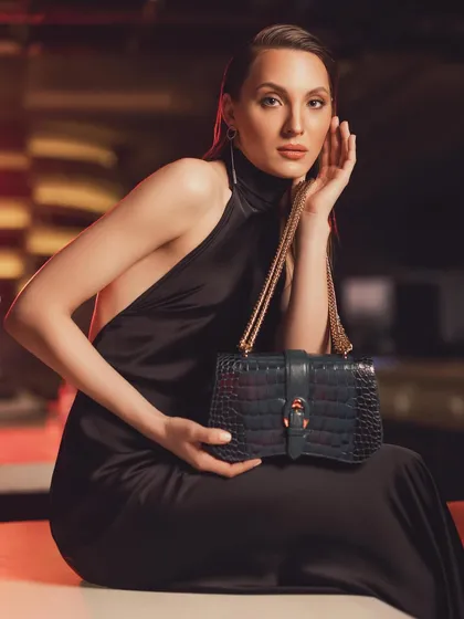 Styling for a luxury brand campaign, this image features a model in a black backless gown holding a crocodile leather handbag, epitomizing chic evening glamour.