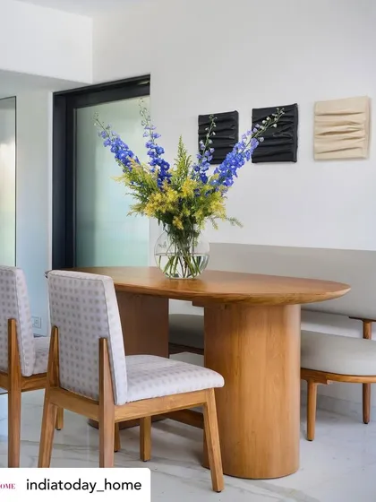 A beautiful shot from the India Today Home feature of our 'House on the Hill' dining area. The space combines a sleek wooden table with patterned chairs and fresh flowers, creating an atmosphere of organic luxury.