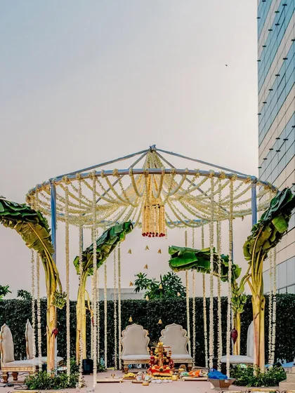 A minimal mandap design that proves simplicity can be stunning. We used fragrant mogra and rose garlands with fresh banana leaves to create a sacred, elegant space that complements the urban backdrop.
