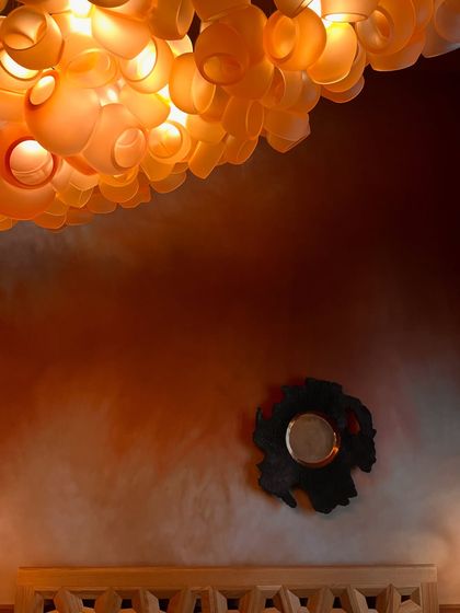 An artistic shot of the Bocci 100 series chandelier, with its warm light casting a soft glow on the wall and ceiling.