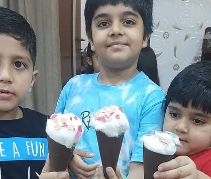 Three young boys proudly showing off the ice cream crafts they made. Grouping students by age helps me tailor the activities to their skill level.