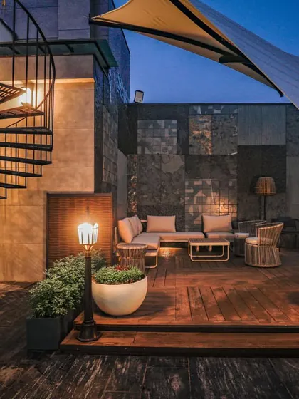 A cozy seating nook on the Vikaspuri terrace, complete with a spiral staircase, a tensile fabric canopy, and warm ambient lighting for evening gatherings.