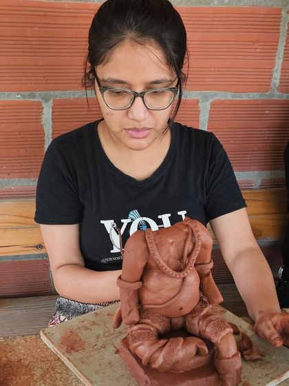 A student concentrating on shaping the torso of her Ganesha. This foundational step is crucial for the final form.