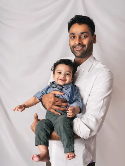 A proud father and his smiling son. The baby boy looks so dapper in his little bow tie and suspenders for this classic portrait.