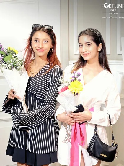 Two happy guests holding bouquets at my Women's Day event. I believe in celebrating my guests, and small gestures like fresh flowers help make everyone feel special and appreciated.