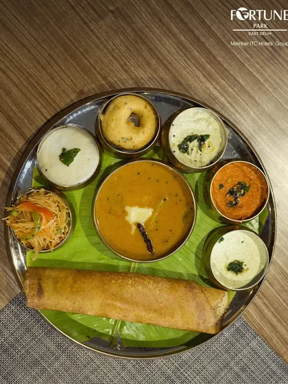 A traditional South Indian breakfast thali from our buffet, featuring a mini dosa, vada, and an assortment of chutneys and sambar.