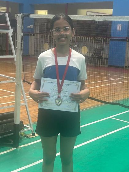 One of our dedicated students proudly displaying her medal and certificate after a successful school tournament. We support players at all levels of competition.