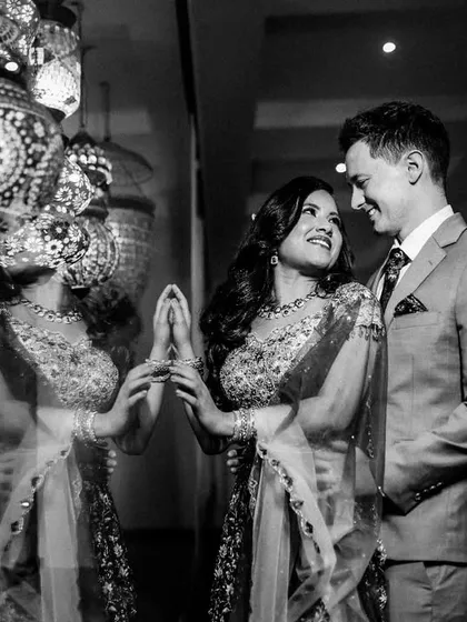 A creative black and white portrait using reflections to capture the couple amidst ornate lanterns, adding an artistic touch to their reception photos.