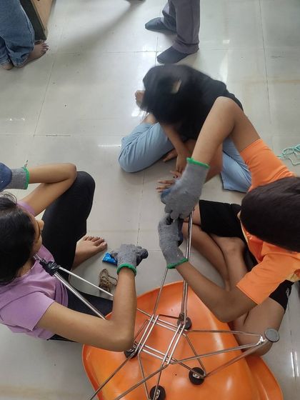 Teamwork in action as a group of kids work together to repair a chair. This exercise teaches not only mechanical skills but also communication and collaboration as they figure out the problem together.