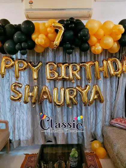 A simple and stylish balloon garland for a 7th birthday. We installed this black and orange garland above the curtains in a living room, complemented by foil letters for the name and a number balloon.