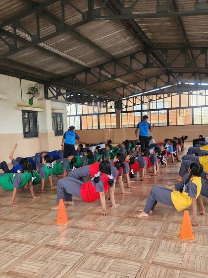 A large group of students holds the reverse table-top pose. This image showcases the scale of our wellness programs and our ability to engage many students at once.